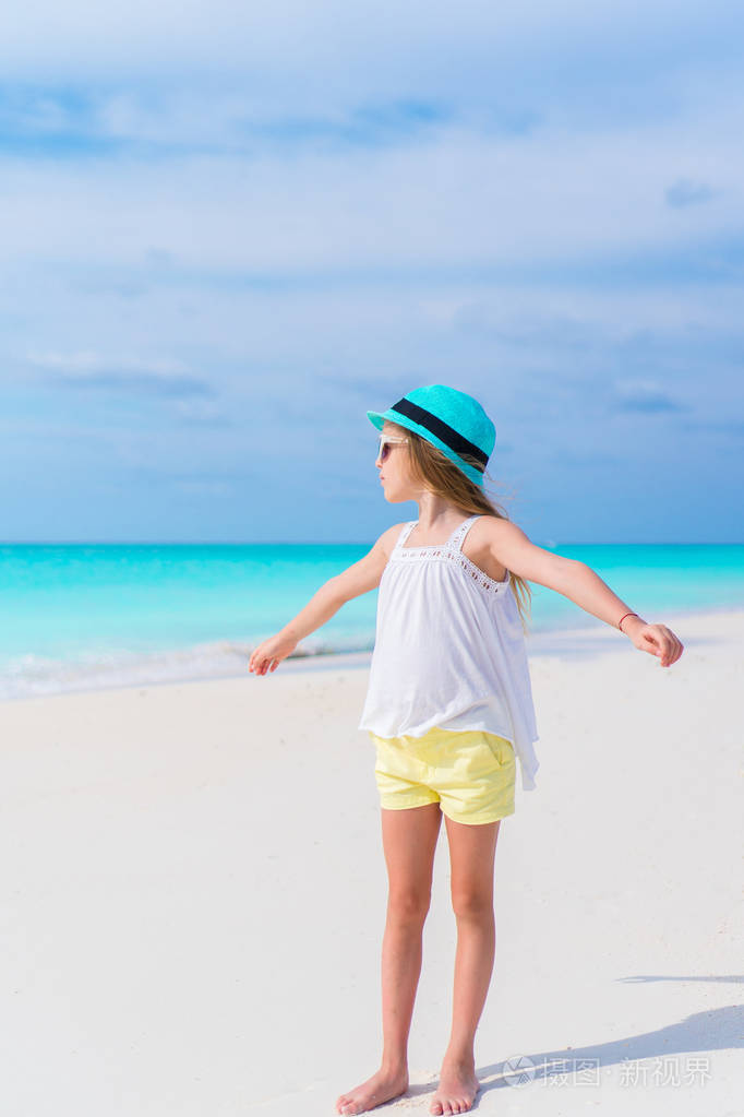 快乐可爱的小女孩在白色的沙滩上行走