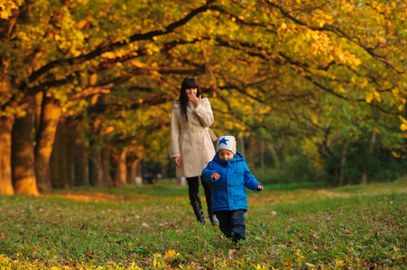母亲带着孩子在秋天公园散步