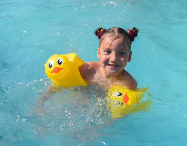 一个阳光明媚的享受玩和在游泳池里打开一个微笑的小女孩照片