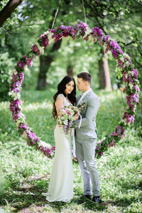 时尚婚礼情侣站在淡紫色的大圆圈前