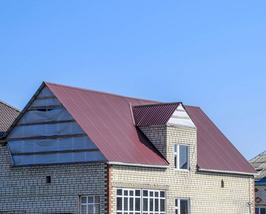 房子的煤渣砖。房子与塑料窗和屋顶的波纹板。屋面的金属型材波浪形状上有塑料窗户的房子