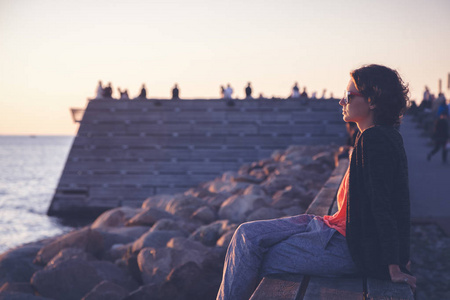美丽的年轻女子坐在海边看日落