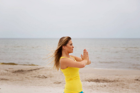 做瑜伽锻炼在海滩上的年轻女子