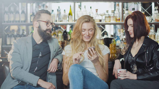 3 人公司的朋友正在酒吧柜台，后面拍照，微笑和快乐情绪的面孔看着智能手机的相机