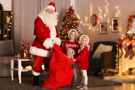 圣诞老人展示礼物给可爱的孩子在房间里与美丽的圣诞装饰品