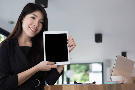 女商人在工作场所举行数字平板电脑。年轻女人表演