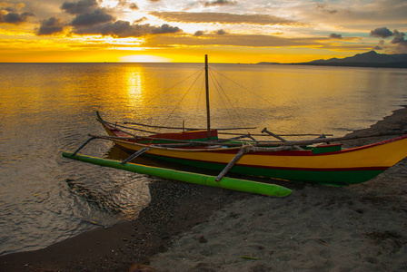 在海滩上美丽的夕阳。站在岸边的本地船只。香兰，班乃菲律宾