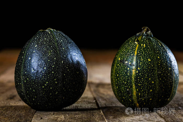 迷你南瓜在木桌前黑色背景上