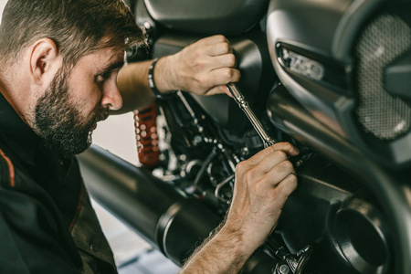 特写镜头的摩托车修理工修理摩托车在汽车商店