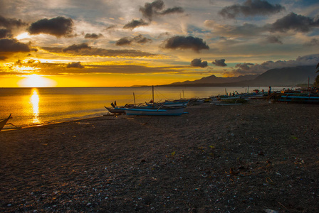 在海滩上美丽的夕阳。站在岸边的本地船只。香兰，班乃菲律宾