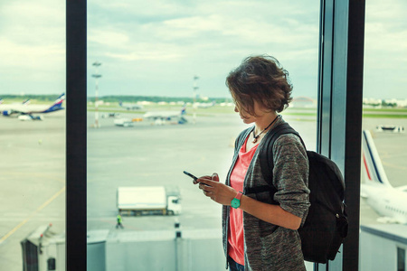 年轻女子旅客在机场的一部手机在手中