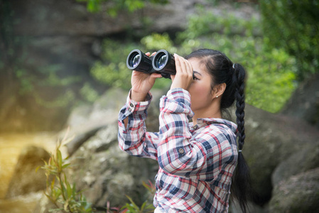 年轻的亚洲旅行者女人双筒望远镜在仰望幸福