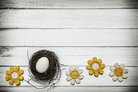 鸡蛋与花围绕着木制的背景上的窝里