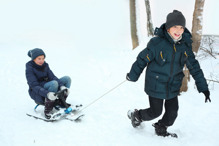 兄弟姐妹男孩和女孩骑雪滑板车在冬季白色背车