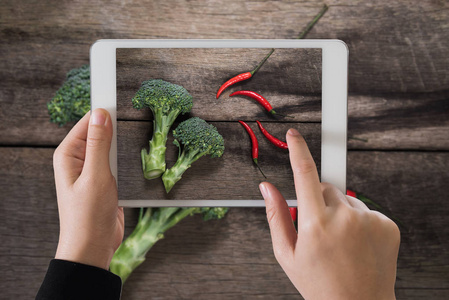 ipad 上木表背景照相的新鲜的西兰花和辣椒。顶视图