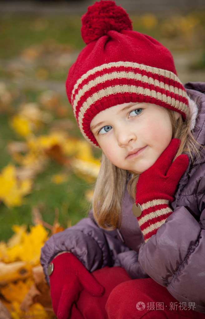 小女孩坐在中间秋天的落叶