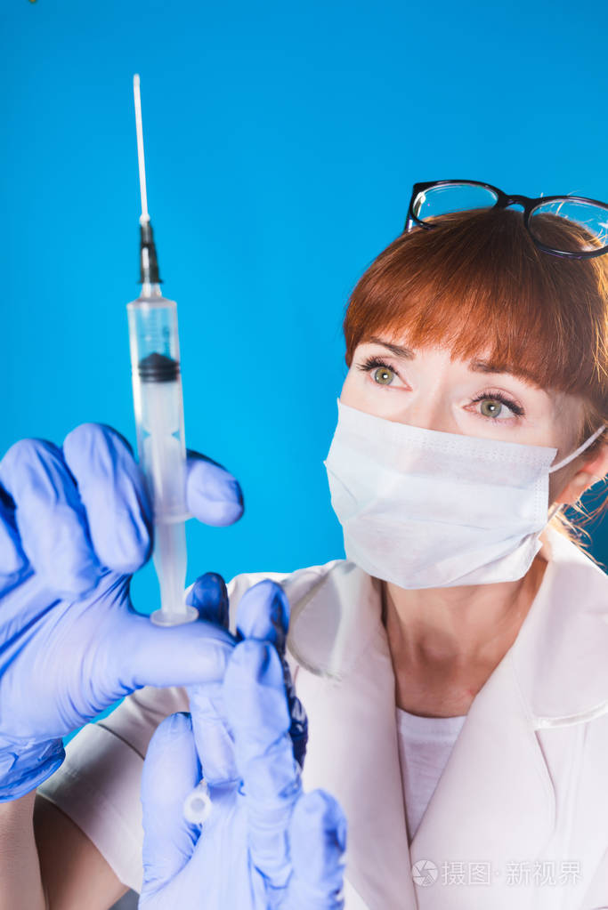 一个女医生服药在注射器和仔细看针,孤立