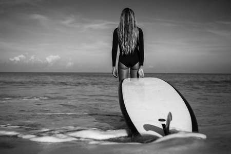 冲浪板站在海滩上的女人