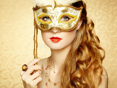 戴着神秘金色威尼斯面具的美丽年轻女子照片