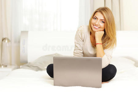 女人坐在床上拿着笔记本电脑