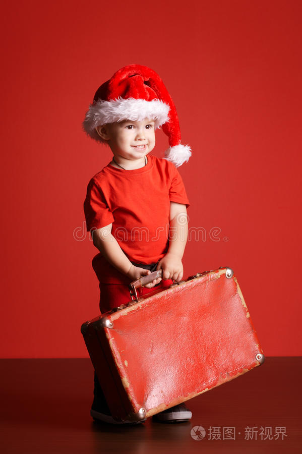 小可爱的小男孩拿着红色的手提箱