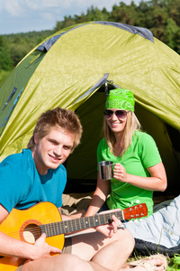 野营情侣玩吉他的帐篷农村