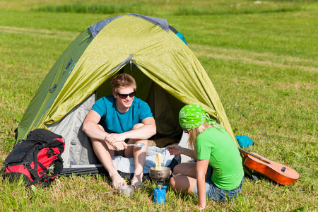 烹饪餐帐篷外面的年轻野营夫妇