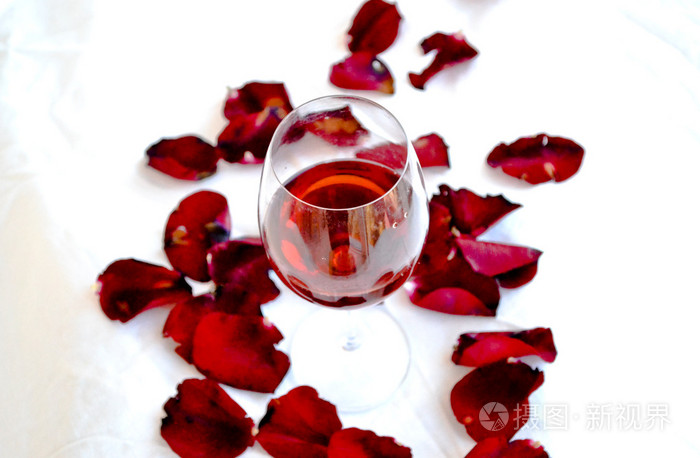 玫瑰花瓣中的红酒杯