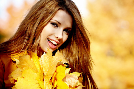 秋天的年轻女人在手叶和秋天黄色枫叶雀鳝