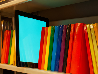 彩色图书和电子书阅读器在架子上的行