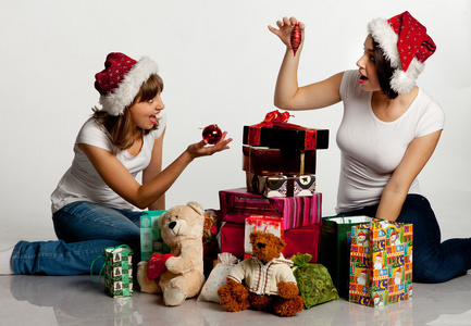 两个微笑打开包装礼物的圣诞女孩