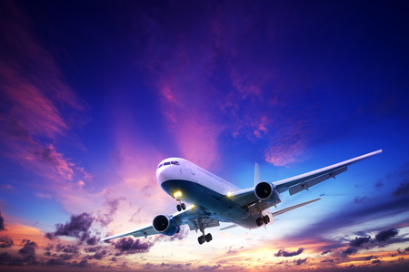 喷气式飞机巡航在落日的天空照片