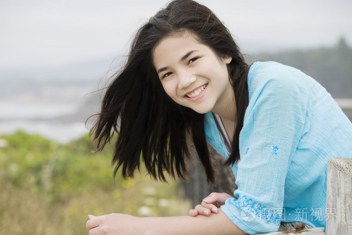 青春期的混血儿女孩与一个美丽的微笑可以俯瞰海洋岸