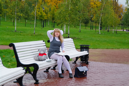 坐在秋天的公园长椅上的女学生