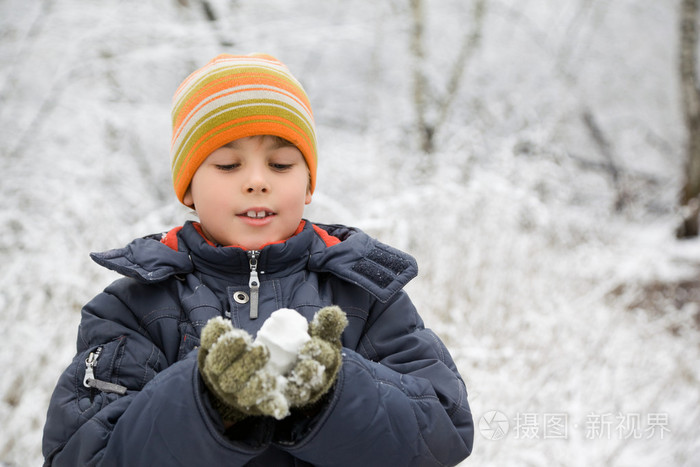 男孩在冬季养在木材中的手雪球
