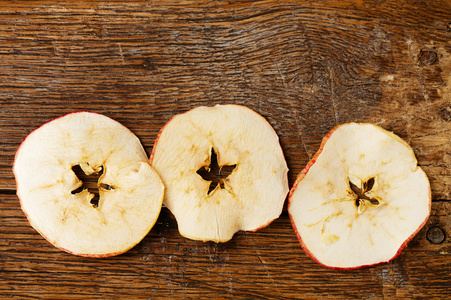 旧木桌上的三个干的苹果切片图片