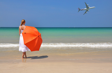 在沙滩上的橙色雨伞的女孩