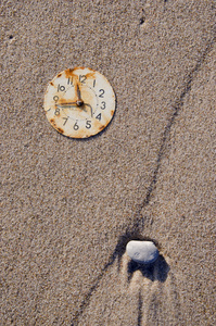 海的海滩沙子上生锈的时钟表盘