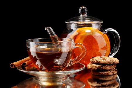 玻璃茶壶和杯子与饼干孤立在白色和黑色水果茶