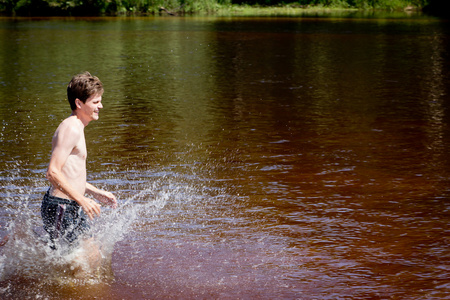 开心的人在夏季通过河流水中水运行