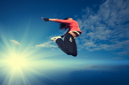 体育女子跳跃和飞翔在天空和太阳