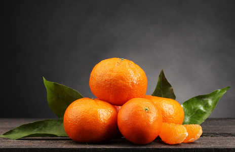 用灰色的背景上的木桌上叶子的橘子
