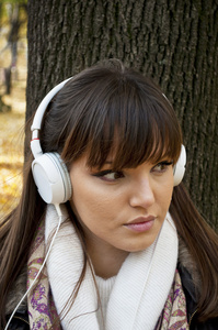 用耳机听音乐在公园中的年轻有魅力的女人