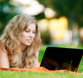 年轻女子在公园的笔记本电脑
