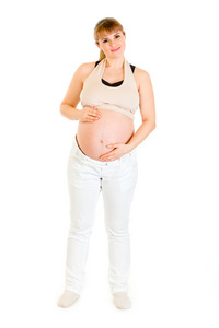 微笑迷人的孕妇举行她的肚子上白色隔离