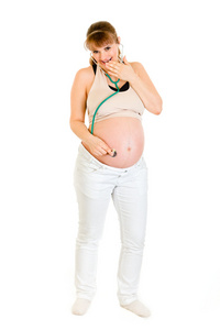 在她的肚子上拿听诊器的惊讶怀孕女性