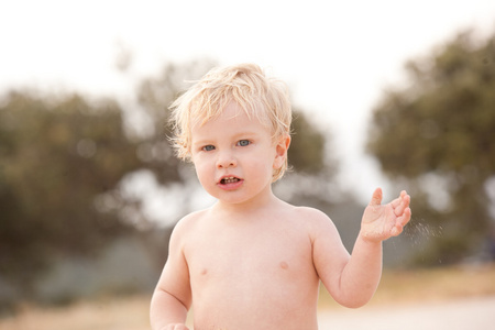 一个小金发蓝眼一岁的男孩在海滩上