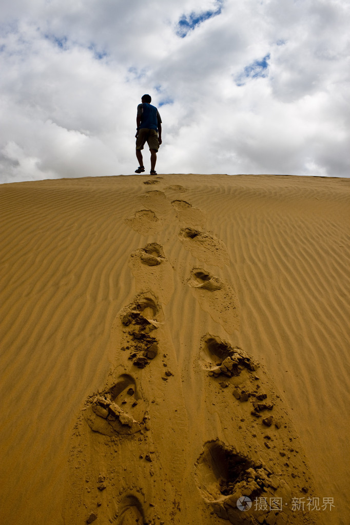 一个沙丘上行走的人照片-正版商用图片0vqugb-摄图新视界
