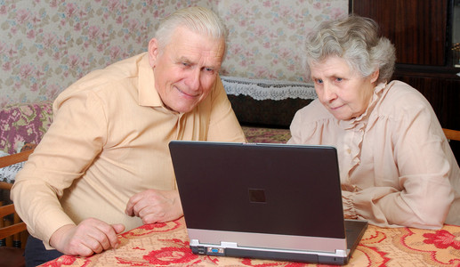 老夫妇看起来到笔记本电脑与积极关注