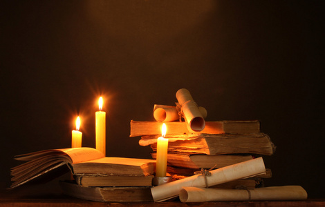 在黑暗中桩的旧书籍与蜡烛和滚动